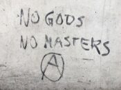The reality of the American Dream has lead me to see the shining edifice in the harsh light of truth. Photo of Graffiti "No Gods, No Masters" and anarchy symbol at central bus station ZOB in Munich, Germany. 